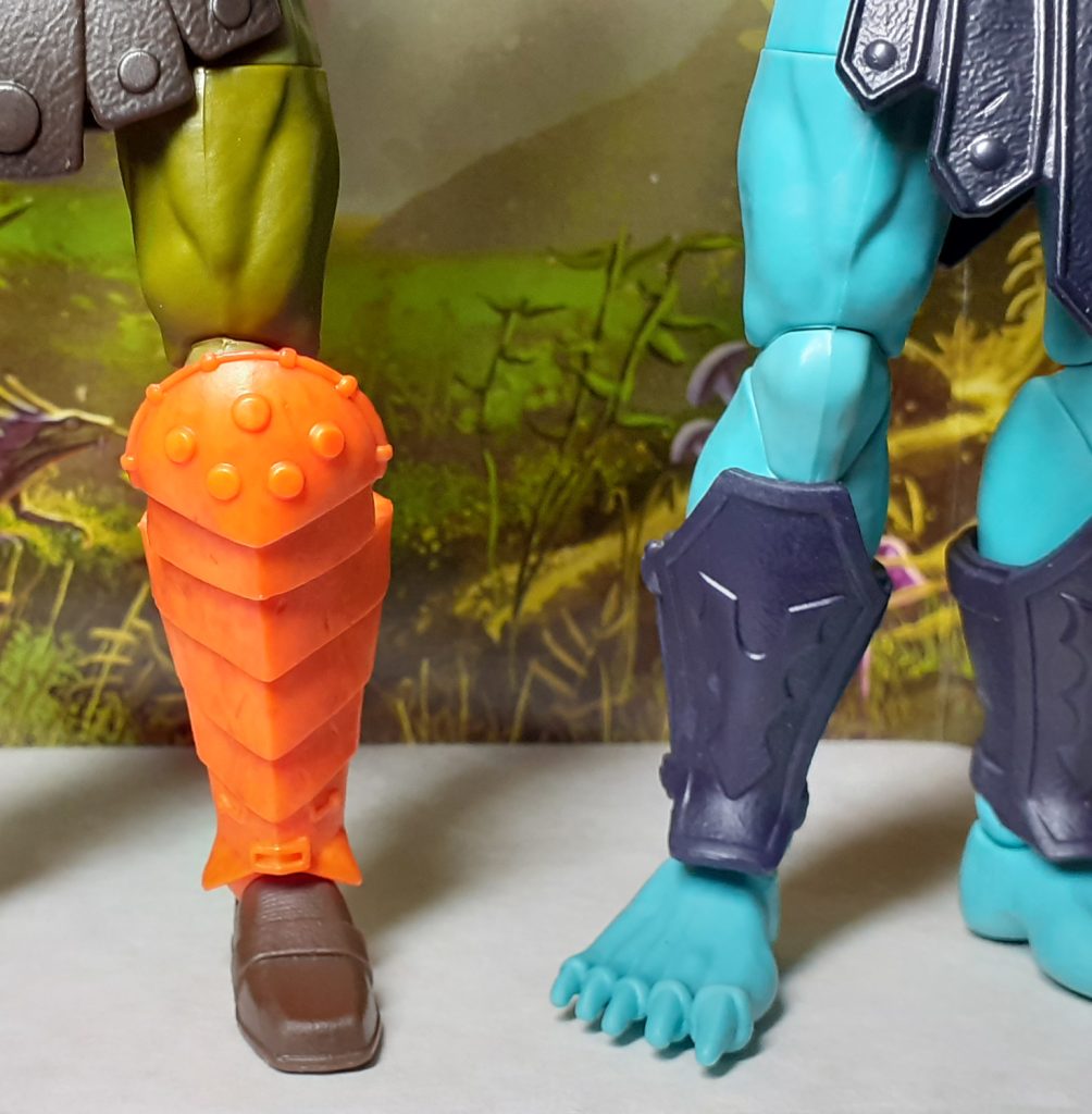 A close up photo of the left leg of Man-at-Arms alongside the right leg of Barbarian Skeletor. Apart from the lower leg armour, the mould for the legs of both figures seems to be same.