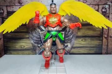 A photo of the Sun-Man figure posed using a transparent plastic flight stand. The figure is again lifted slightly in the air by the stand.