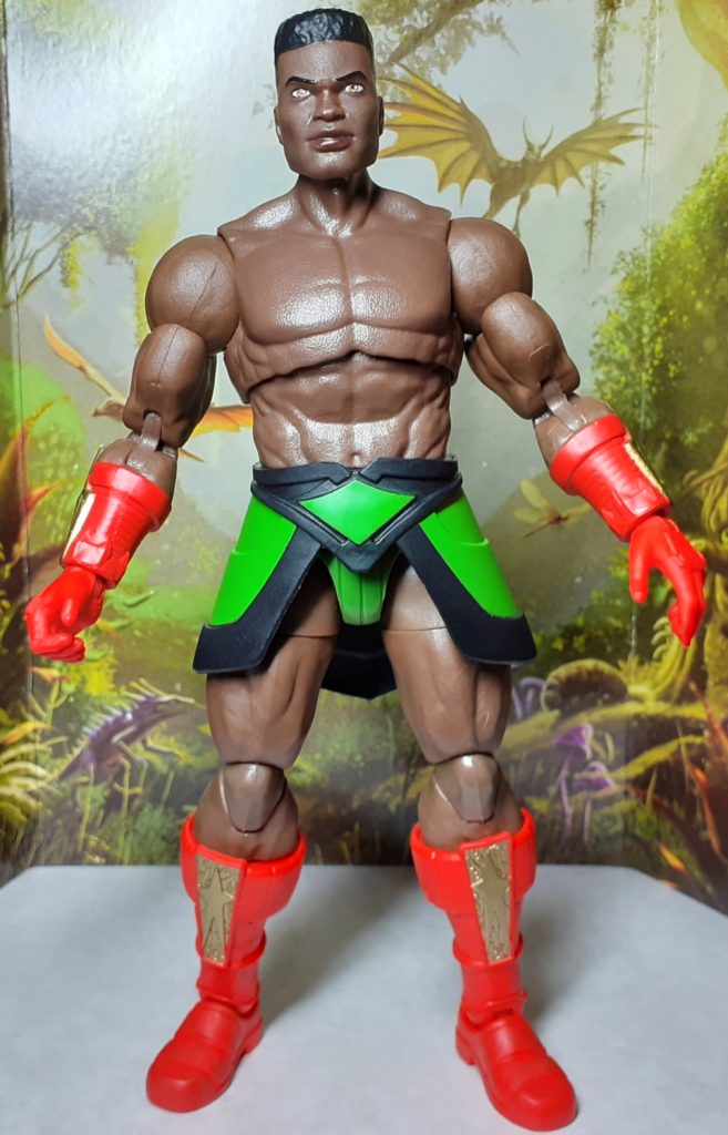 A photo of the Sun-Man figure with the wings and torso armour removed. The figure has a slightly shiny brown skin tone and non-removable bright orange-red gauntlets and boots. The figure also has a short skirt which is black and a lime green.