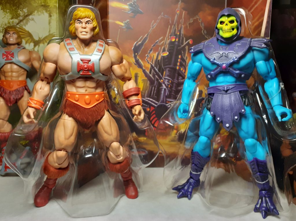 The versions of He-Man and Skeletor from the special 2022 SDCC box set. Both figures are still sitting in their clear plastic packaging. He-Man is on the left while Skeletor is on the right.