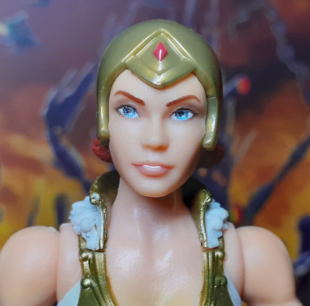 A close up photo of the helmeted head for Vintage Collection Teela. The helmet is moulded in a gold coloured plastic with a red gem on the figure's forehead.