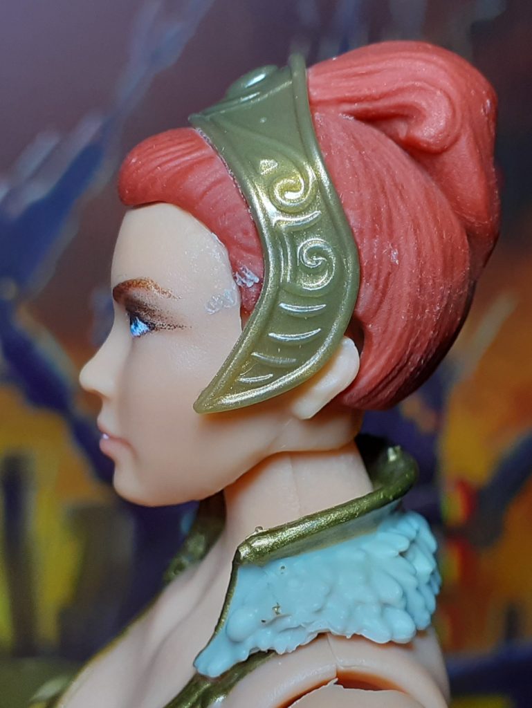 The side view of the alternative head for Vintage Collection Teela. The tiara is quite wide and the red hair sits on top of the head in more a bun.