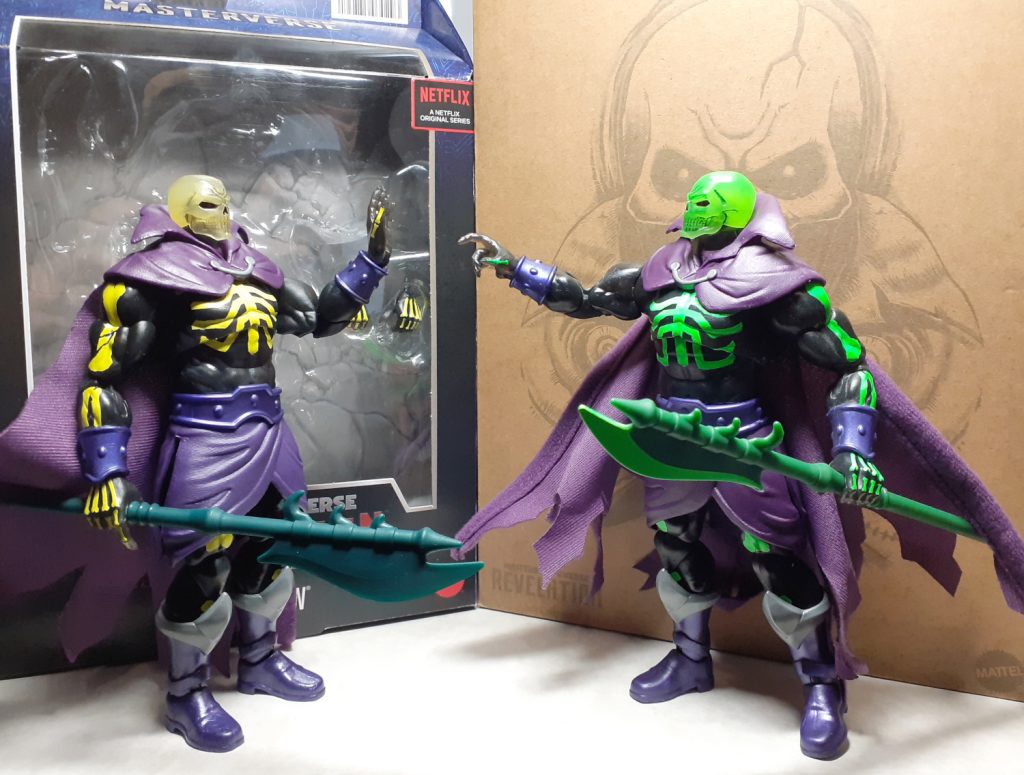 A photo of the two Scare Glow figures gesturing at each other. On the left is the standard retail release holding up its open hand as though it has had enough of the other figure. On the right is the SDCC version of Scare Glow with bright green, day glow painted on bones. This figure is pointing at the other Scare Glow. Behind both figures are their respective boxes.