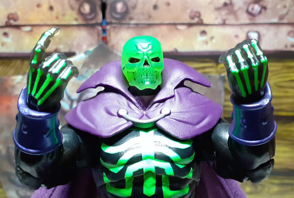 The SDCC Scare Glow figure holding up the pair of gripping hands. The right hand has a pointing index finger while the left hand is more closed. Both hands have small hand and finger bones painted on them.