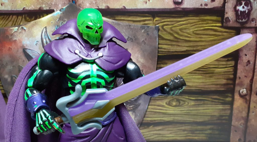 The SDCC Scare Glow holding the Sword of Power in its right hand and gripping the blade in its left. This version of the Sword has a large oversized hilt section and a blade that's split into two halves - one half is a translucent purple and the other is a light yellow in colour.
