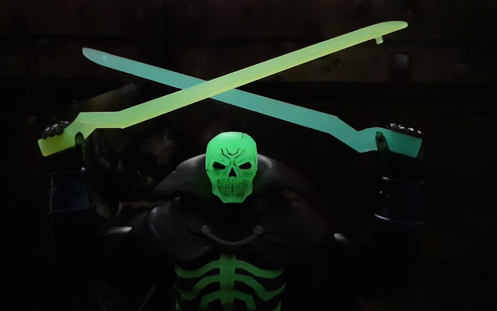 The Scare Glow figure holding the two halves of the Sword of Power over its head again but in this photo, the lights have been turned off. In the dark Scare Glow's head is glowing but so are the two halves of the Sword.