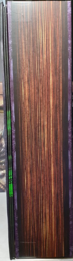 The display box for the figure is designed to look like an ancient book. This is a bit more apparent in this photo of the side of the box. It's been drawn and painted to look like yellowed and creased page edges.