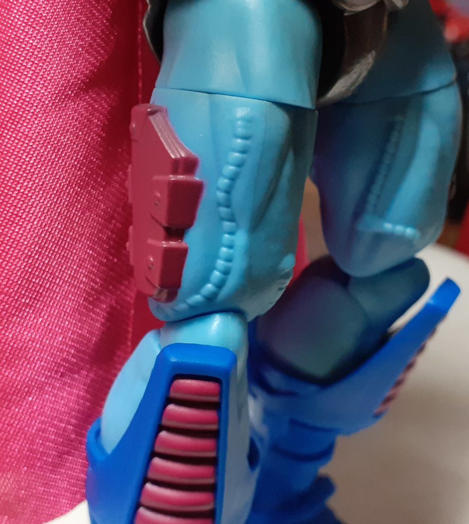 A close up look at the figure's right leg. As with the arms, tubes and wires have been moulded into the sculpt. In addition to these, on the outer side of the thigh is a piece of plate armour painted a magenta colour.