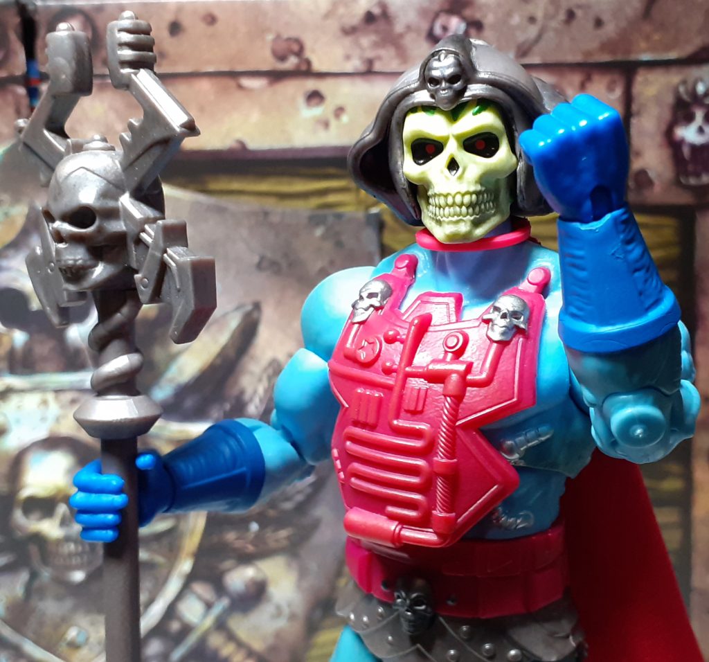 A photo of the top half of the Skeletor figure. The figure is hold its left fist up at the viewer as though it is shaking it. In its right hand is the Havoc Staff.