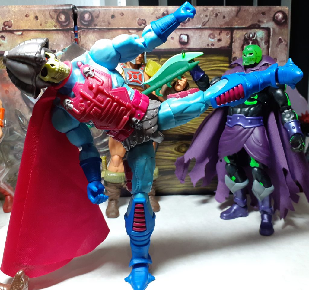 Another photo showing off the figure's articulation. Here, New Adventures Skeletor is posed in a high kick position with its left leg high in the air and pointing to the viewer's right. In the background can be seen the Scare Glow and Viking He-Man figures.