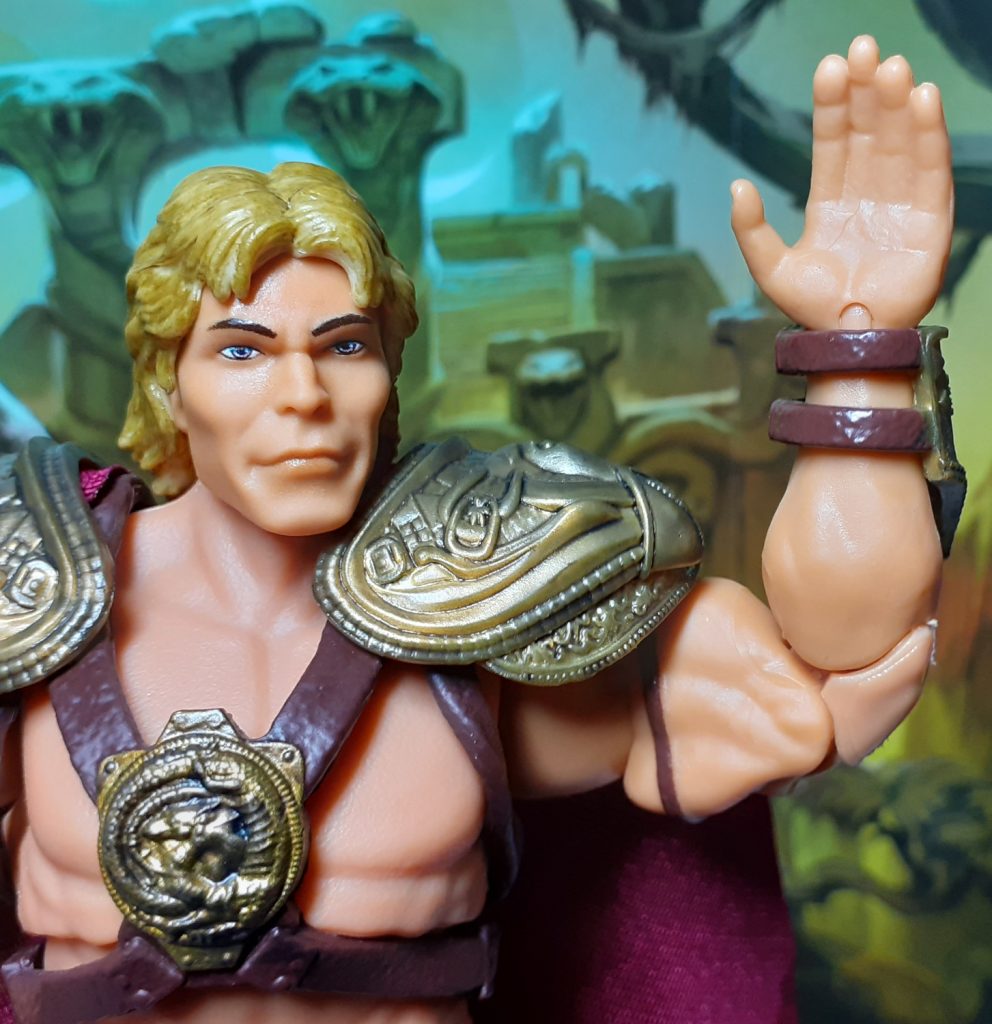 The 1987 Movie He-Man figure holding up its left arm and open hand. The arm is bent at the elbow at about 90 degrees.