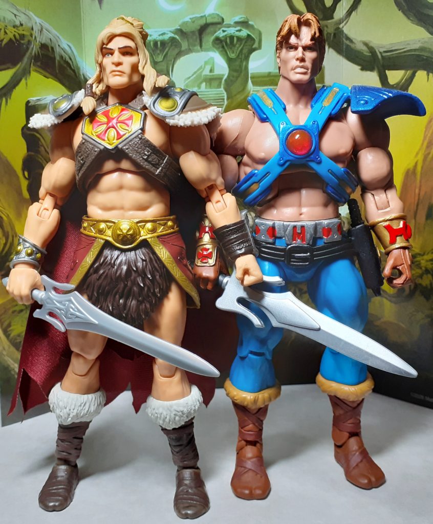 A side by side height comparison photo of the King Grayskull and Classics He-Ro II figures. On the left of the photo is King Grayskull while on the right is He-Ro II. He-Ro II is about the same height as King Grayskull but has a much more muscular build. This figure is wearing a blue chest harness with a central red gem.
