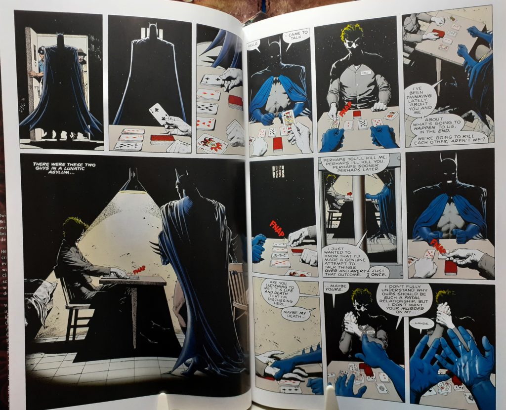 Two interior pages from the Batman The Killing Joke Deluxe Edition book. These pages feature the Batman entering a prison cell and sitting down at a table opposite from the Joker. The Joker appears to be playing a game of cards.